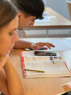 Lernende mit Buch und Smartphone